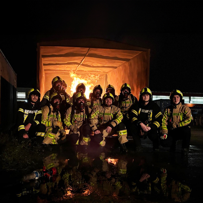 Gruppenfoto Einsatzabteilung vor brennendem Container